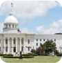 A view of the Alabama State Capitol building, featuring its iconic dome and classical design in a vibrant setting