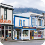 A charming street with several shops, set against the backdrop of a stunning mountain landscape